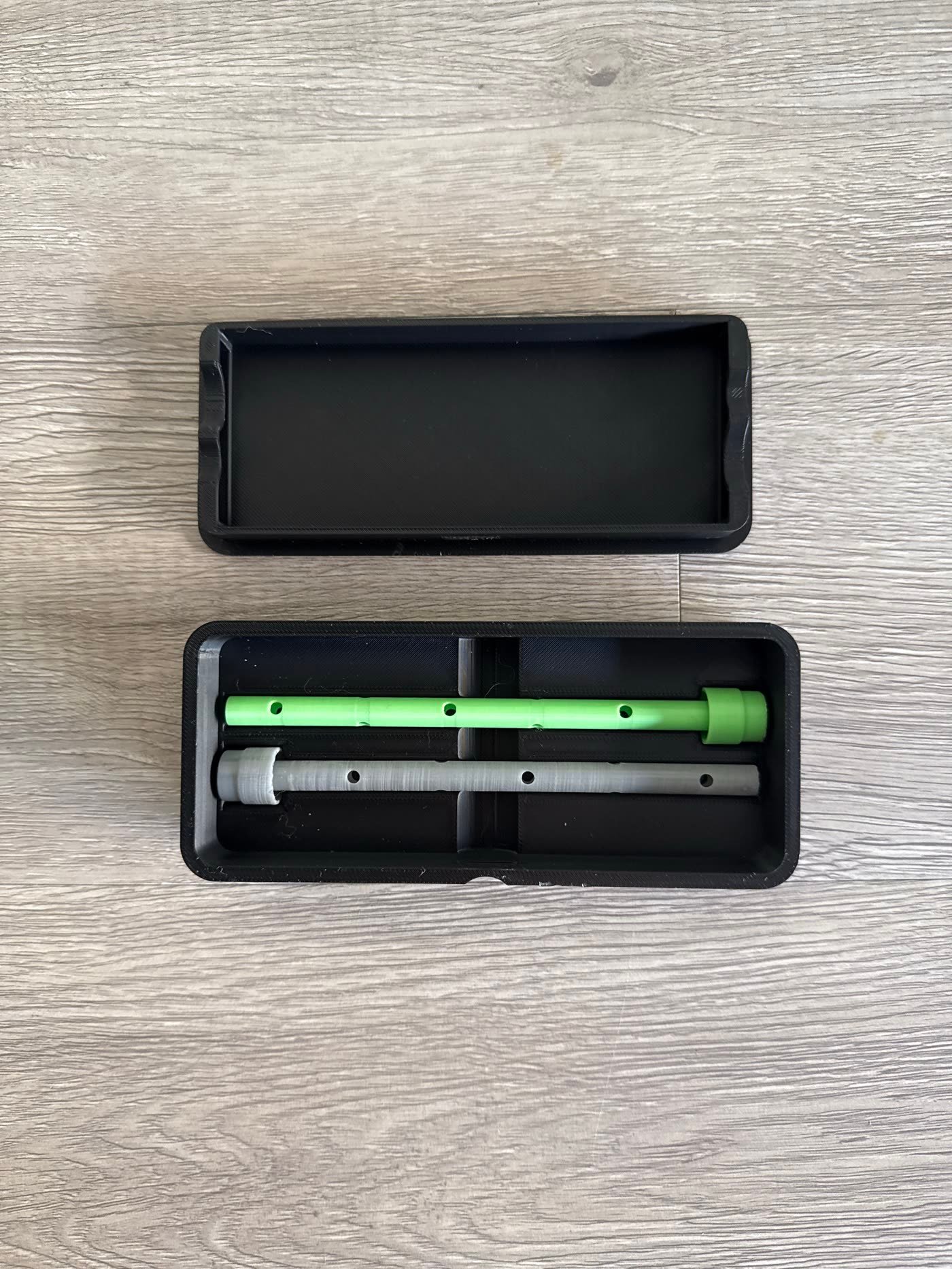Two Sip Smart prototype straws, one green and one gray, resting in an open black carry case